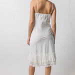 Back view of rice slip with ruffles on model wearing natural sandals, against a white background.
