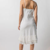 Back view of rice slip with ruffles on model wearing natural sandals, against a white background.
