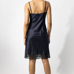 Back view of midnight susan slip on model wearing natural sandals. against a white background.