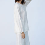 Side view of rice tunisian top on model wearing rice pants, against a white background.