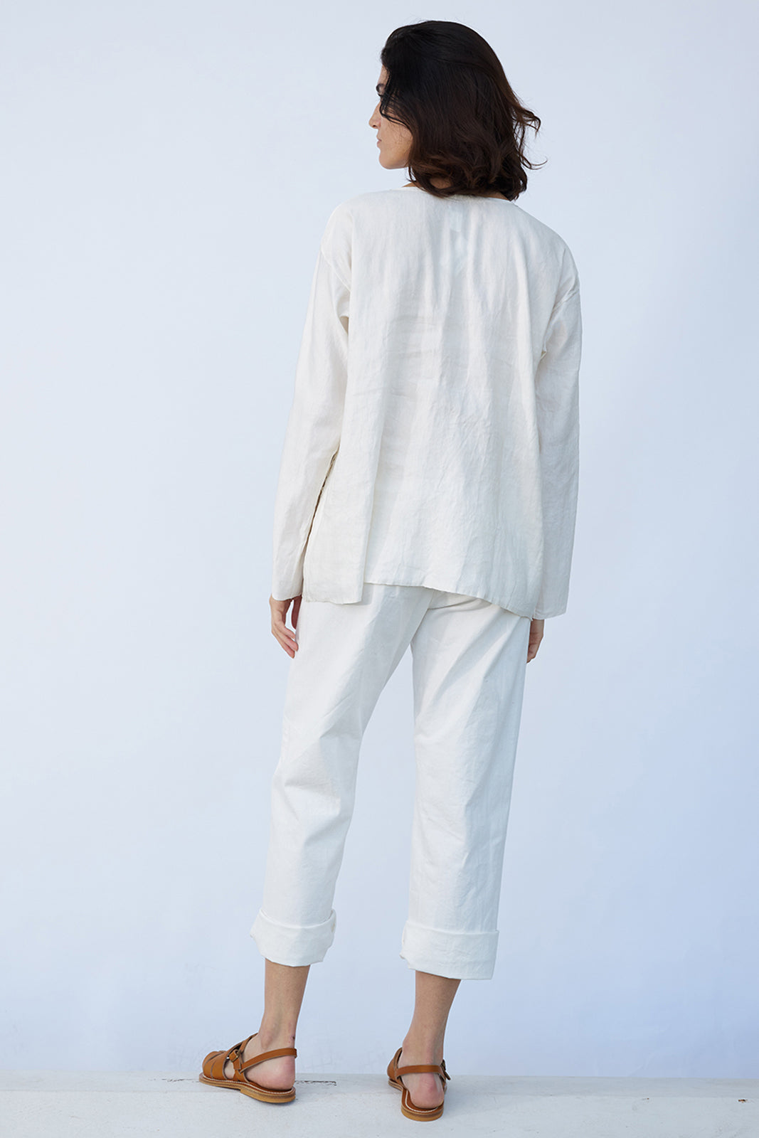 Back view of rice tunisian top on model wearing rice pants and natural sandals, against a white background.
