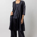 Front view of midnight wrap dress worn open on model wearing midnight pants and natural sandals, against a white background.