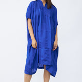 Front view of cobalt yoruba tunic on model wearing natural sandals, against a white background.