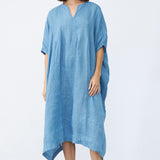 Front view of denim yoruba tunic on model wearing leather sandals, against a white background.