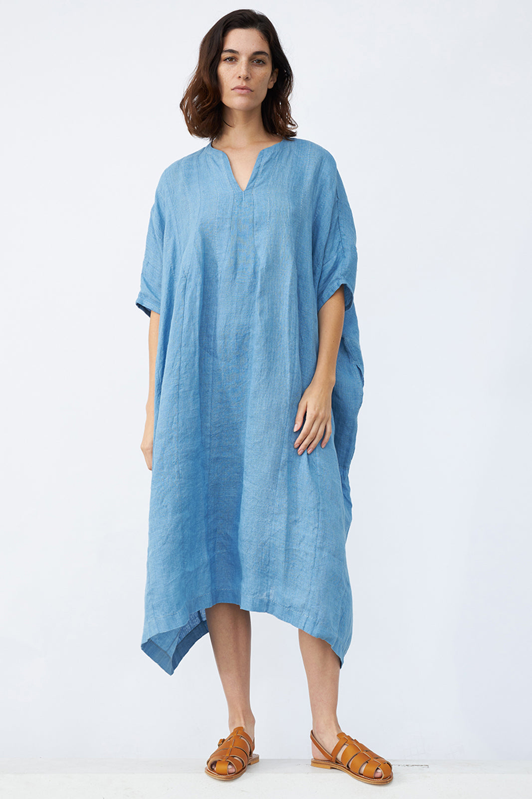 Front view of denim yoruba tunic on model wearing leather sandals, against a white background.