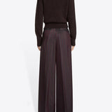 Back view of burgundy penn wide leg pant n model wearing brown sweater and floral scarf, against a white background.
