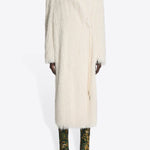 Front view of white Rivla Fringed Coat on model wearing green print boots against a white background.