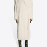 Front view of white Rivla Fringed Coat on model wearing green print boots against a white background.