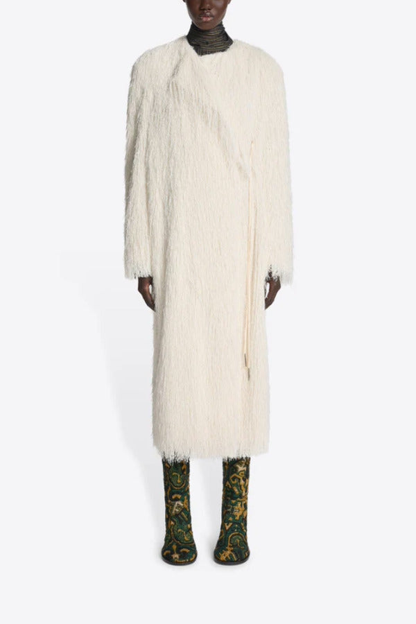 Front view of white Rivla Fringed Coat on model wearing green print boots against a white background.