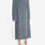 Side view of Dark Grey Rivla Fringed Coat on model wearing white heels, against a white background.