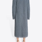 Back view of dark grey Rivla Fringed Coat on model wearing white heels, against a white background.