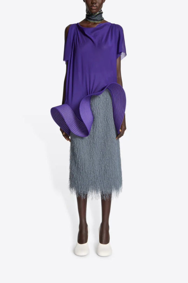 Front view of dark grey sonka tris fringed skirt on model wearing purple top with white heels, against a white background.