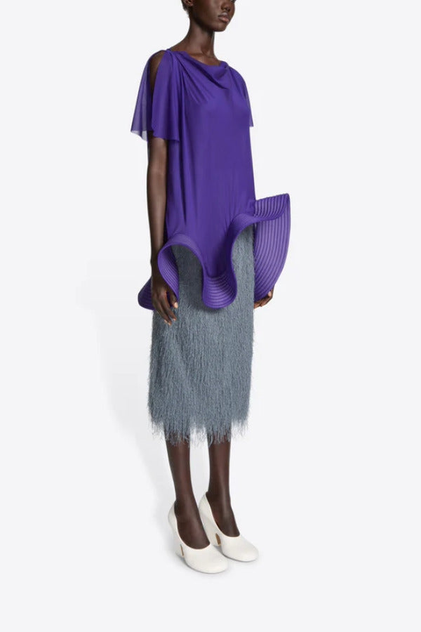Side view of dark grey sonka tris fringed skirt on model wearing purple top and white heels, against a white background.