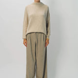 Front view of vanilla cashmere cn kimono sleeve sweater on model wearing sand pants, against a white background.