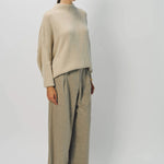 Side view of vanilla cashmere cn kimono sleeve sweater on model wearing sand pants, against a white background.
