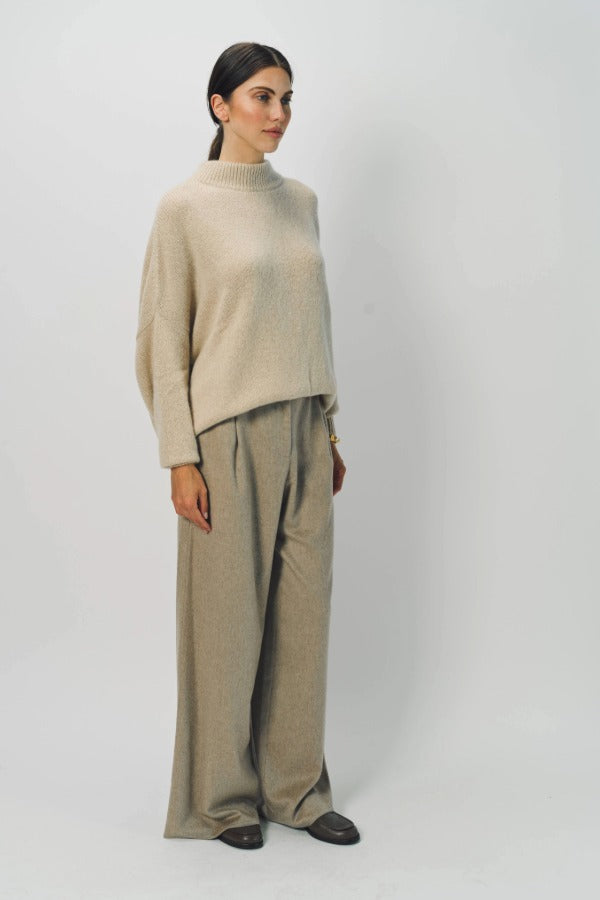 Side view of vanilla cashmere cn kimono sleeve sweater on model wearing sand pants, against a white background.