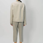 Back view of oatmeal cashmere double face jean jacket on model wearing stone pants, against a white background.