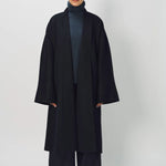 Front view of midnight long kimono coat on model wearing navy turtleneck and navy pants, against a white background.