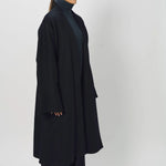 Side view of midnight long kimono coat on model wearing navy turtleneck and pants, against a white background.