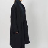 Side view of midnight long kimono coat on model wearing navy turtleneck and pants, against a white background.