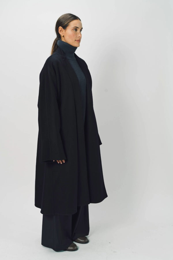 Side view of midnight long kimono coat on model wearing navy turtleneck and pants, against a white background.