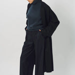 Front slanted view of midnight long kimono coat on model wearing navy turtleneck and pants, against a white background.