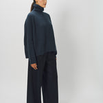 Side view of midnight ls t-neck raglan sweater on model wearing navy pants, against a white background.