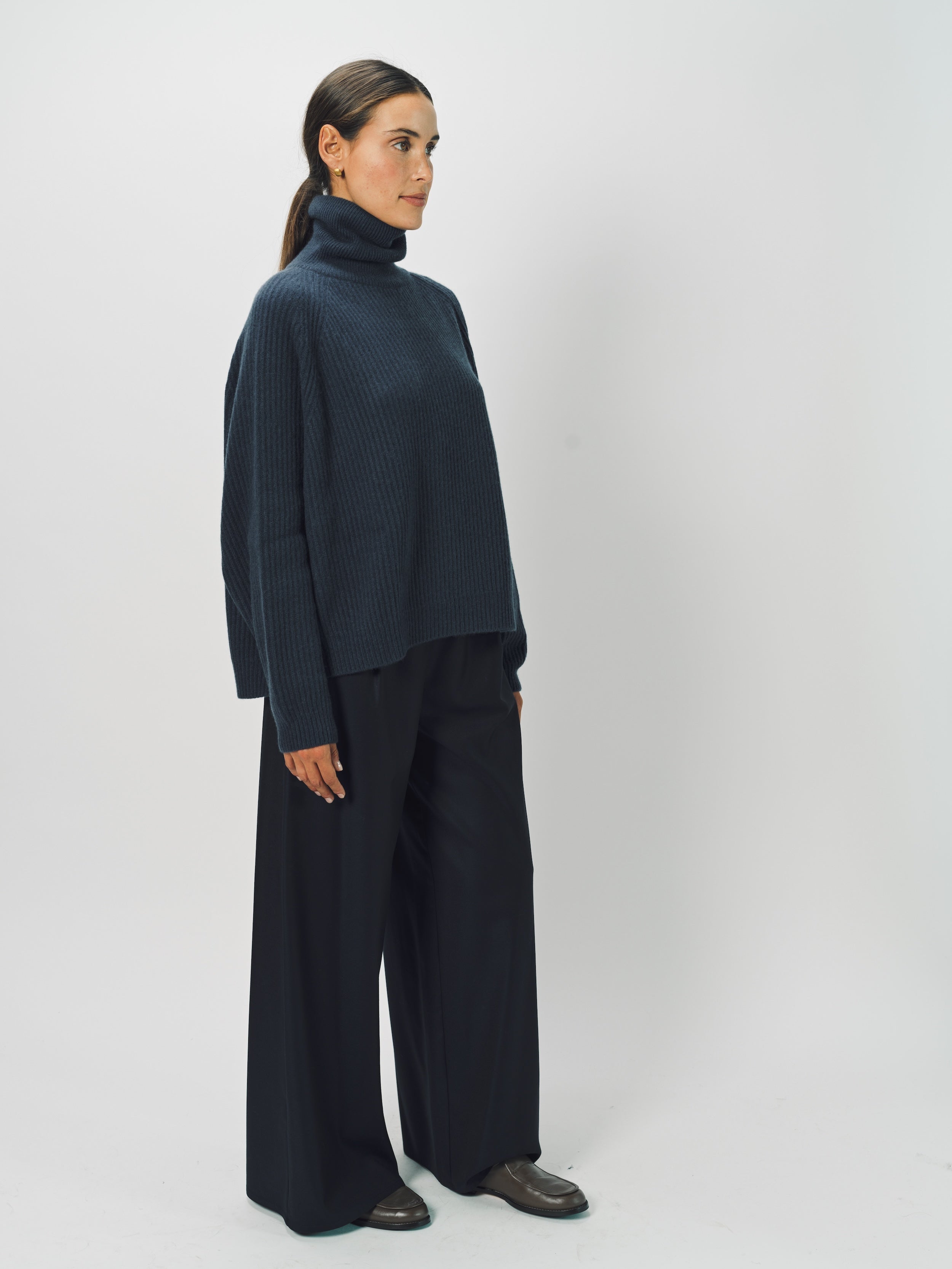 Side view of midnight ls t-neck raglan sweater on model wearing navy pants, against a white background.