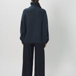 Back view of midnight ls t-neck raglan sweater on model wearing navy pants, against a white background.
