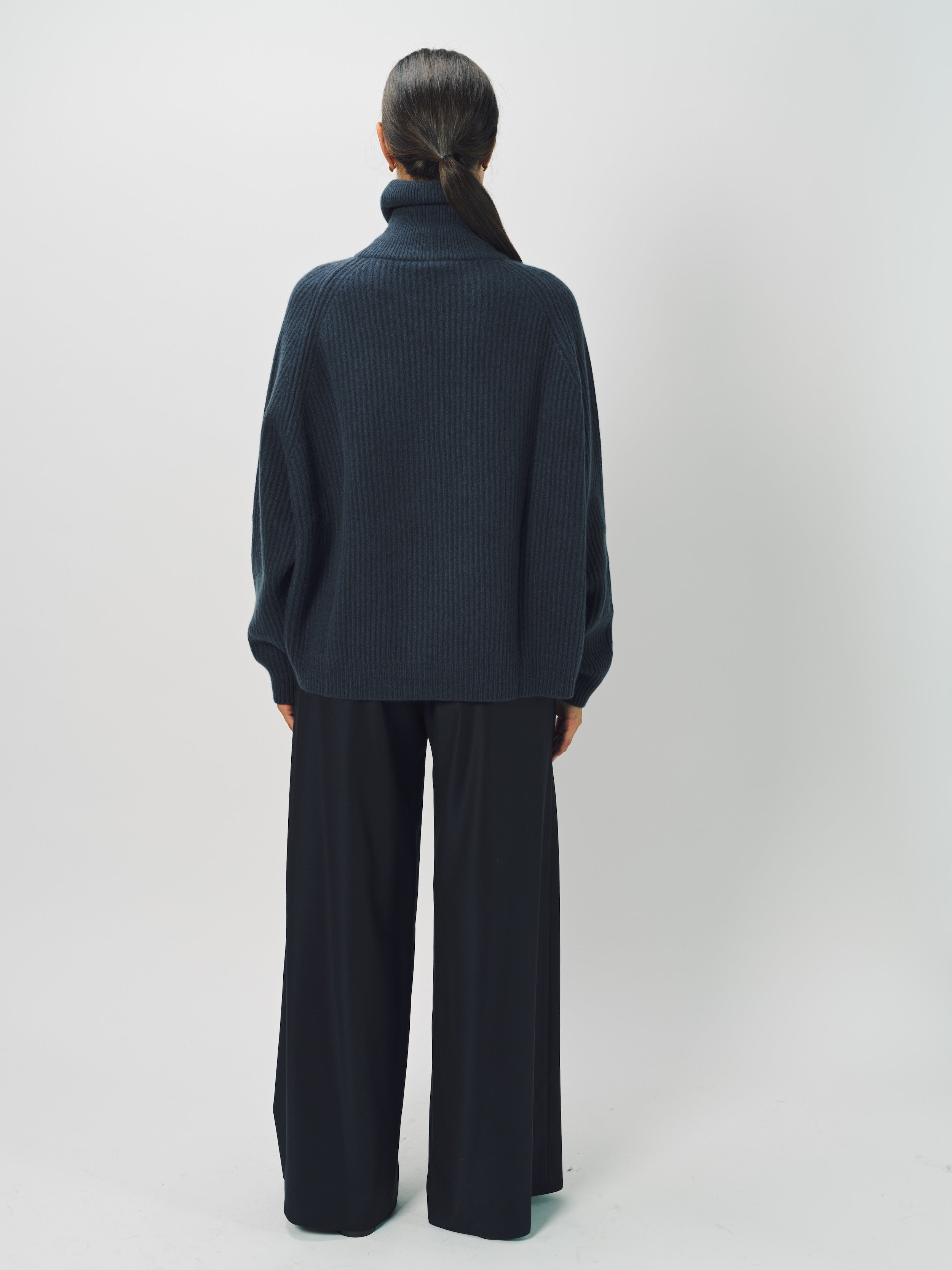 Back view of midnight ls t-neck raglan sweater on model wearing navy pants, against a white background.