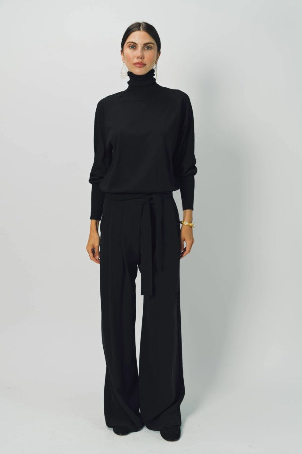 Front view of black ls t-neck raglan sweater on model wearing black pants, against a white background. 