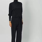 Alternate front view of black ls t-neck raglan sweater on model wearing black pants, against a white background.