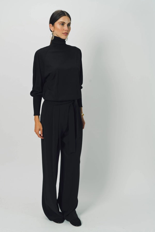 Alternate front view of black ls t-neck raglan sweater on model wearing black pants, against a white background.