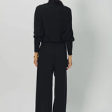 Back view of black ls t-neck raglan sweater on model wearing black pants, against a white background.