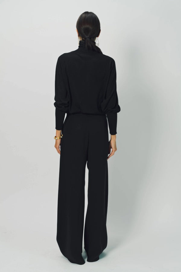 Back view of black ls t-neck raglan sweater on model wearing black pants, against a white background.