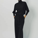 Alternate front view of black ls t-neck raglan sweater on model wearing black pants, against a white background.