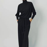 Alternate front view of black ls t-neck raglan sweater on model wearing black pants, against a white background.