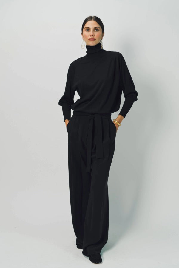 Alternate front view of black ls t-neck raglan sweater on model wearing black pants, against a white background.