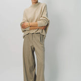 Front view of sand cashmere light full pants on model wearing oatmeal sweater, against a white background.
