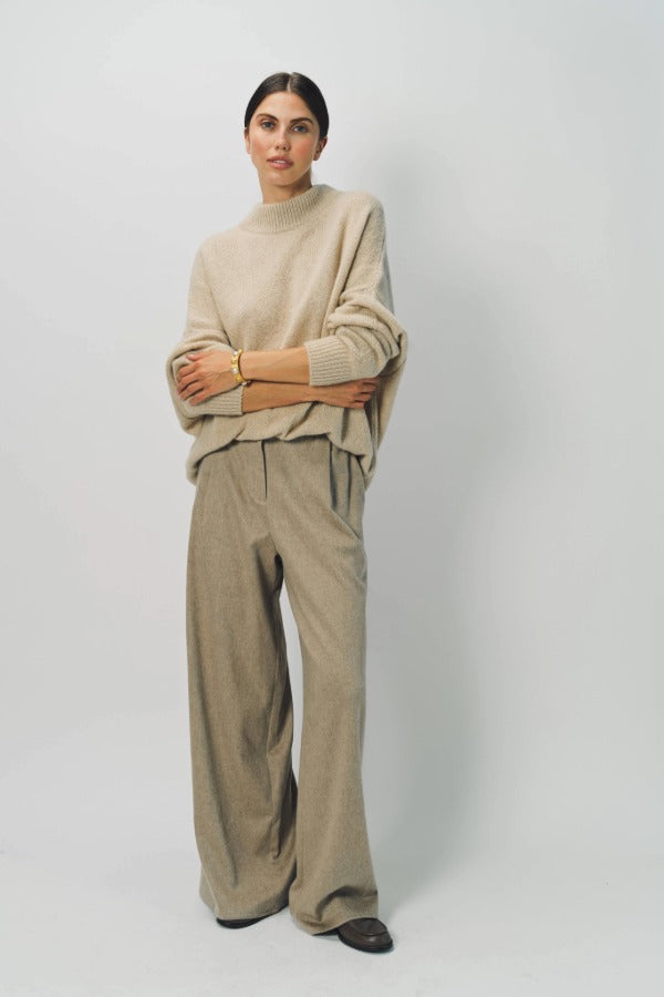 Front view of sand cashmere light full pants on model wearing oatmeal sweater, against a white background.