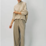 Alternate front view of sand cashmere light full pants on model wearing oatmeal sweater, against a white background.