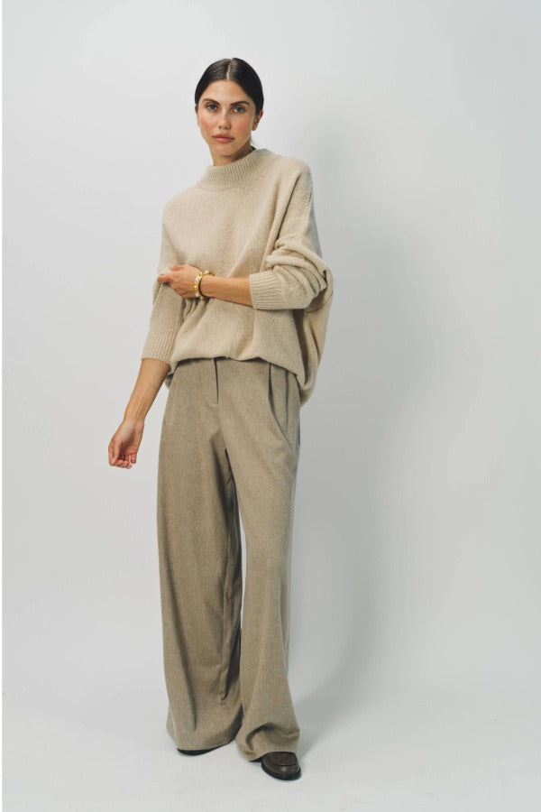 Alternate front view of sand cashmere light full pants on model wearing oatmeal sweater, against a white background.