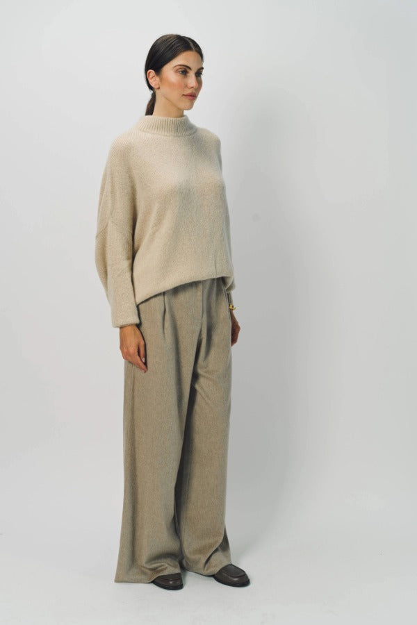 Side view of sand cashmere light full pants on model wearing oatmeal sweater, against a white background.
