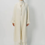 Front view of ivory long cardigan coat on model wearing white turtleneck and pants, against a white background.