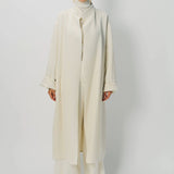 Front view of ivory long cardigan coat on model wearing white turtleneck and pants, against a white background.