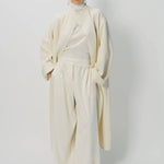 Alternate front view of ivory long cardigan coat on model wearing white pants and turtleneck, against a white background.