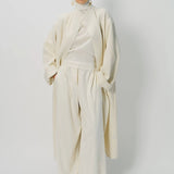 Alternate front view of ivory long cardigan coat on model wearing white pants and turtleneck, against a white background.