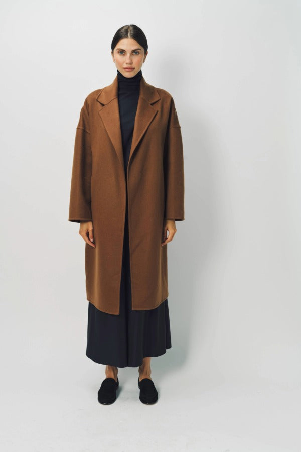 Front view of palissandro oversized coat on model wearing navy turtleneck, pants and loafers, against a white background.