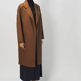 Side view of palissandro oversized coat on model wearing navy turtleneck, pants and loafers, against a white background.