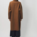 Back view of palissandro oversized coat on model wearing navy pants and loafers, against a white background.